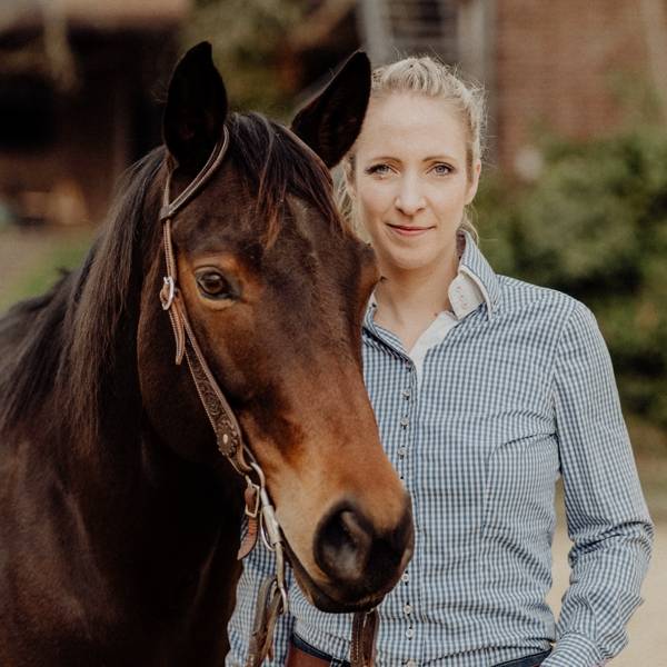 Julia Greb lächelnd neben ihrem Pferd